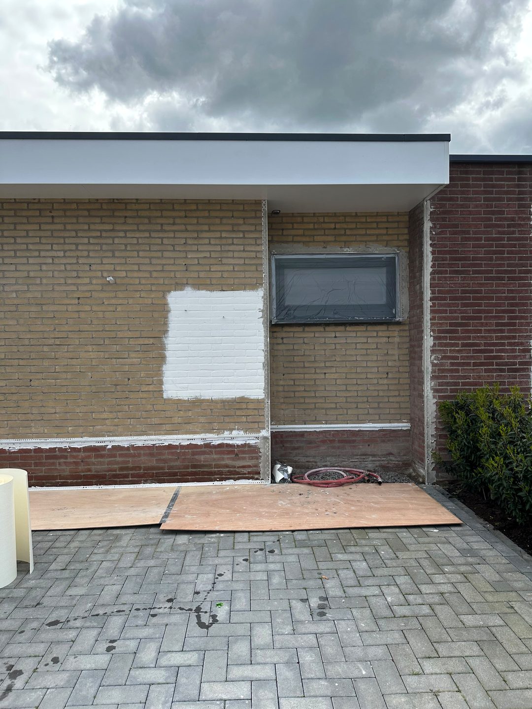 Voorgevel van de bungalow vóór het stucwerk: gele baksteen met een rode plint