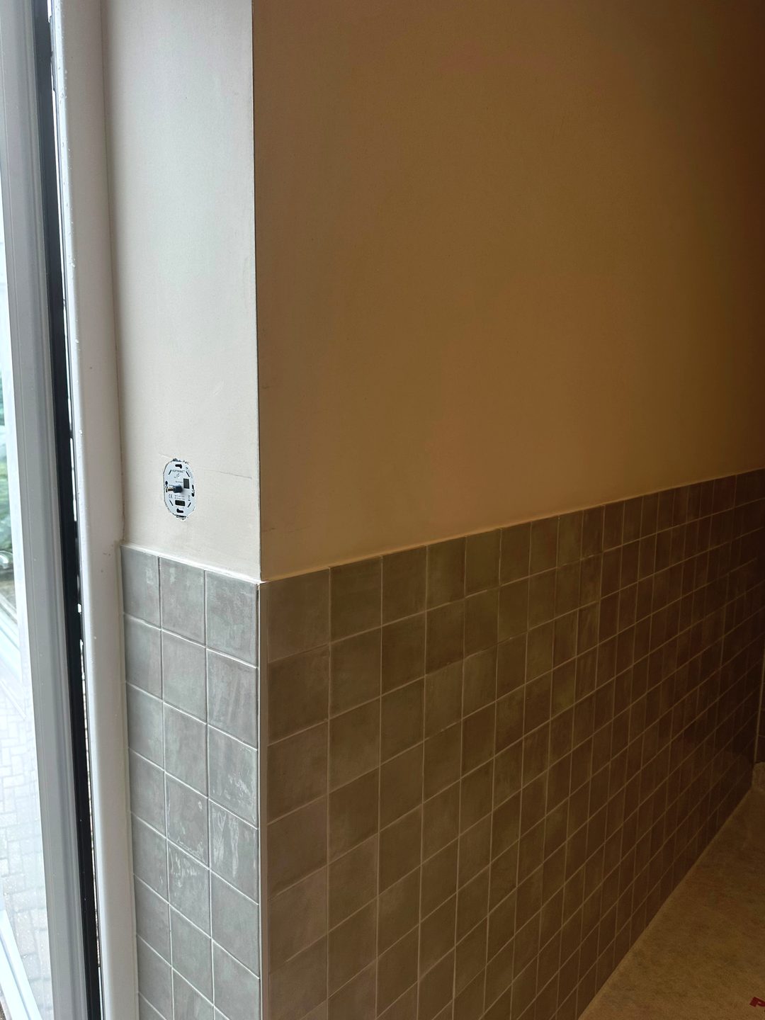 Afgewerkte wand boven halfhoog tegelwerk, strak aansluitend op de hoek