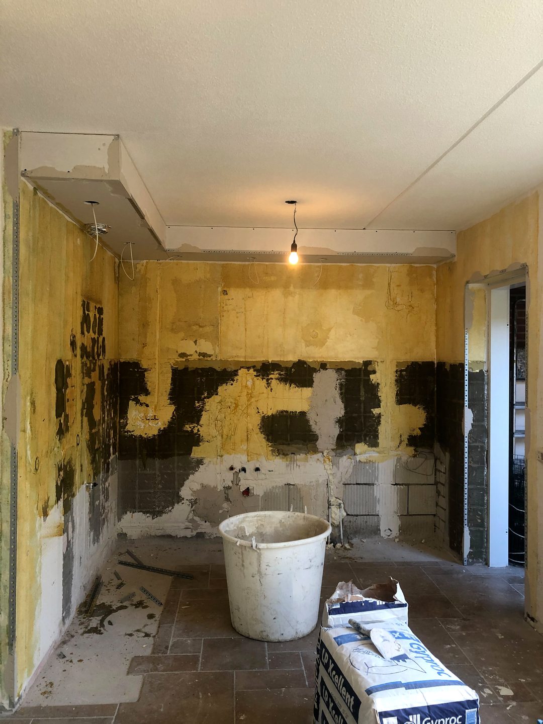 Woonruimte vóór het stucwerk: oude wandlagen en lijmresten van verwijderd tegelwerk